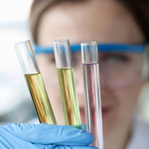 Woman scientist holding test tubes with multicolored liquids in her hands closeup. Laboratory analysis of medicines concept