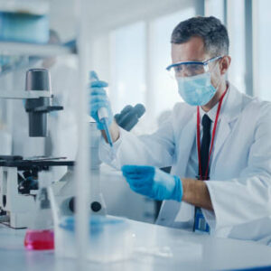 Medical Development Laboratory: Scientist Wearing Face Mask Uses Micro Pipette Dropper to Mix Petri Dish Sample. Specialists Working on Medicine, Biotechnology Research in Advanced Pharma Lab